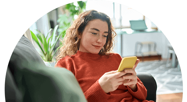 Image of a woman sitting on a sofa and looking at her phone, searching to find a reliable creditor